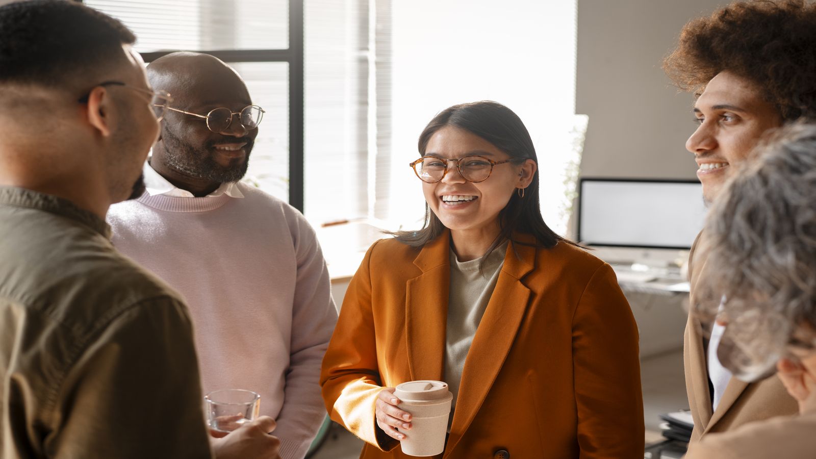 A team of diverse professionals in a casual work setting, sharing authentic conversation