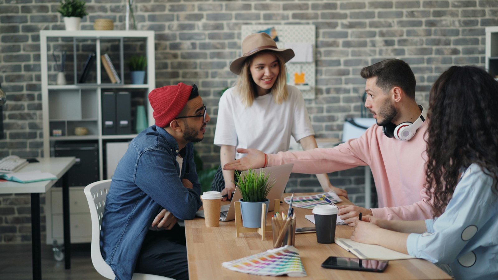 A team collaborating at a table with laptops and headphones